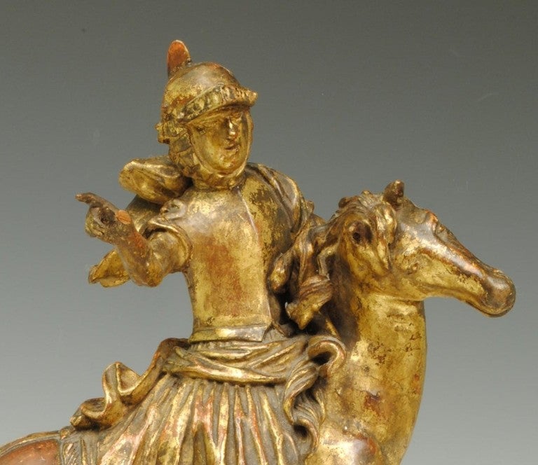 A decorative 18th century carved gilt wood figure of a Knight on a galloping horse. 